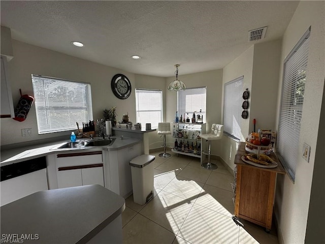 kitchen featuring white cabinetry, light tile patterned floors, hanging light fixtures, and a textured ceiling