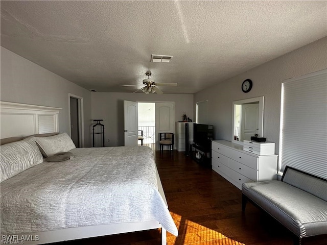 bedroom with ceiling fan, dark hardwood / wood-style flooring, and a textured ceiling