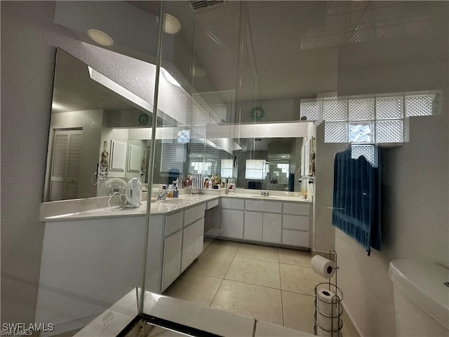 bathroom with tile patterned flooring, vanity, toilet, and walk in shower