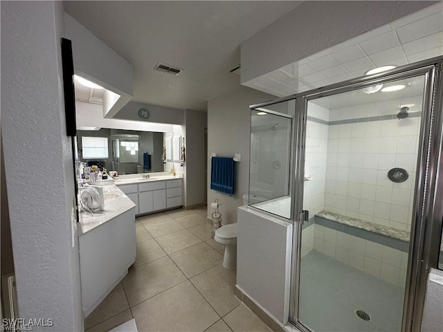 bathroom with tile patterned flooring, vanity, toilet, and a shower with door