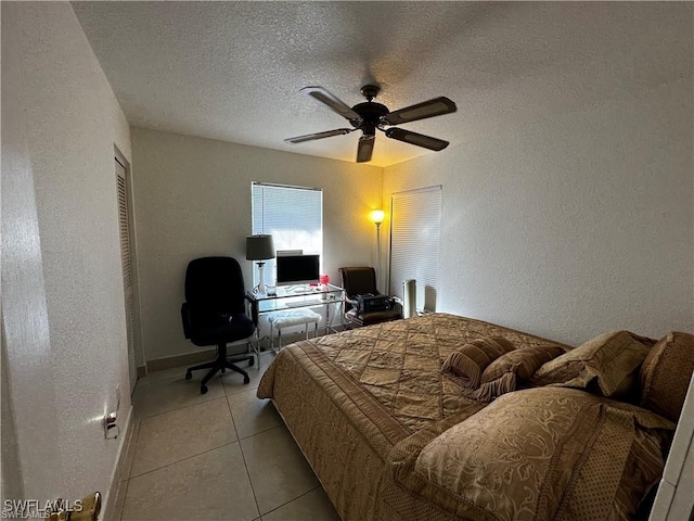 tiled bedroom with ceiling fan and a textured ceiling