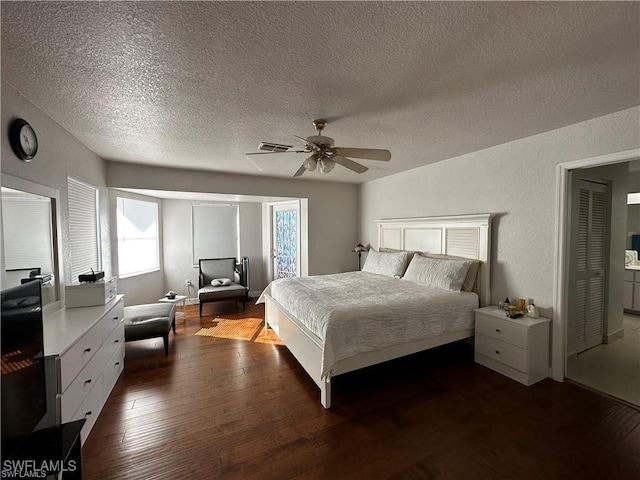 bedroom with ceiling fan, dark hardwood / wood-style flooring, and a textured ceiling