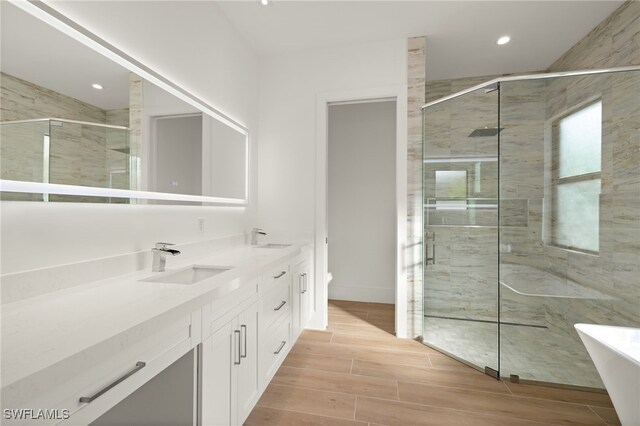 bathroom with hardwood / wood-style floors, vanity, toilet, and a shower with door