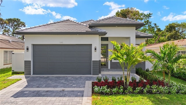 view of front of home with decorative driveway, an attached garage, and stucco siding