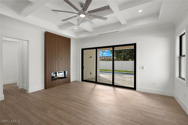 spare room with light wood-type flooring, a glass covered fireplace, and baseboards