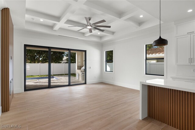 unfurnished living room featuring plenty of natural light, coffered ceiling, and light hardwood / wood-style flooring