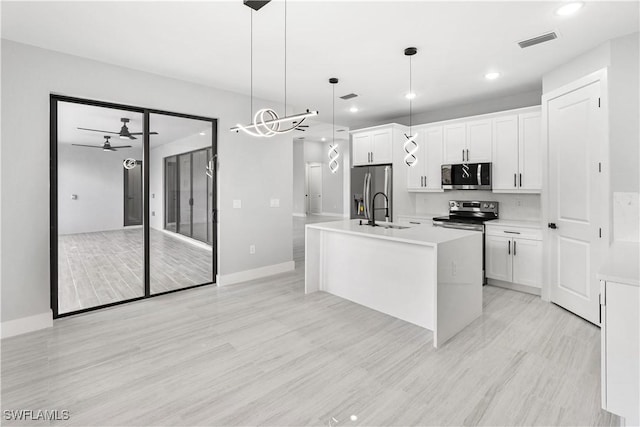 kitchen with white cabinets, appliances with stainless steel finishes, a center island with sink, and pendant lighting