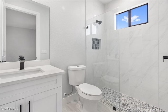 bathroom featuring tiled shower, vanity, and toilet