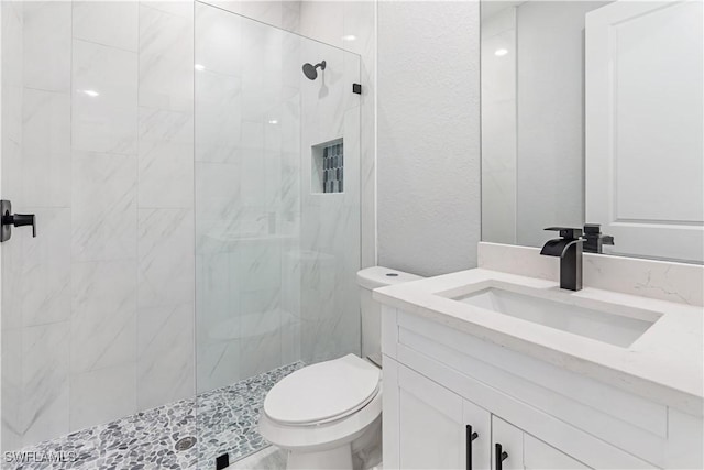 bathroom featuring tiled shower, vanity, and toilet