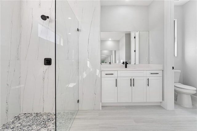 bathroom featuring tiled shower, vanity, and toilet