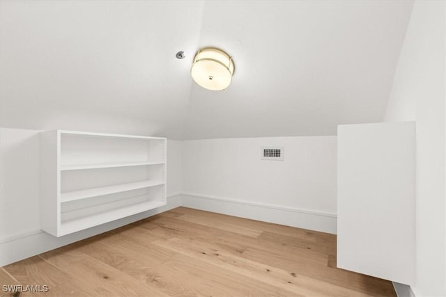 additional living space with light wood finished floors, lofted ceiling, and baseboards