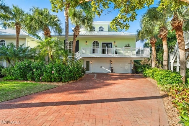 raised beach house with decorative driveway, a garage, stairs, and french doors