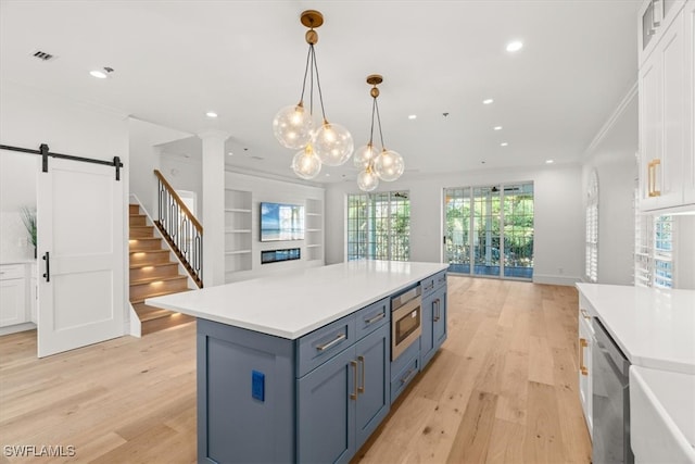 kitchen featuring white cabinets, a barn door, light hardwood / wood-style floors, and appliances with stainless steel finishes