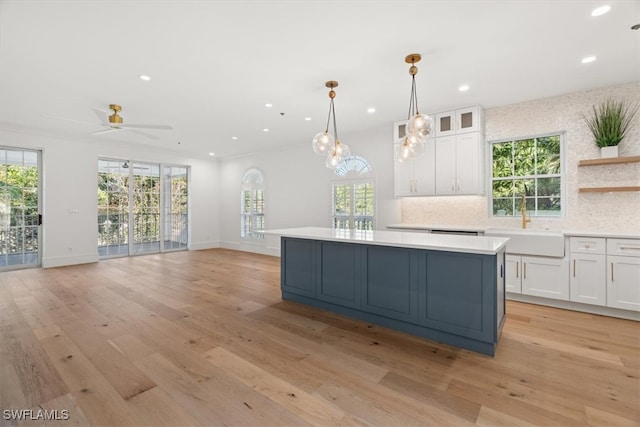 kitchen featuring tasteful backsplash, white cabinetry, ornamental molding, and light hardwood / wood-style flooring