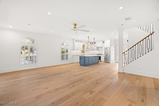 unfurnished living room with decorative columns, ceiling fan, and light wood-type flooring