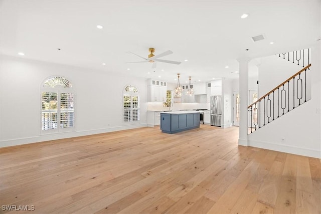 unfurnished living room with ceiling fan, light wood finished floors, stairs, recessed lighting, and baseboards