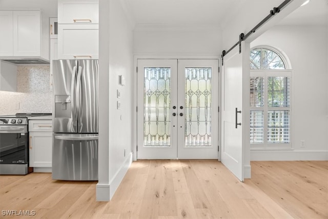 entryway with a barn door, crown molding, french doors, and light wood-type flooring