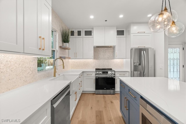 kitchen with light hardwood / wood-style flooring, light stone countertops, decorative light fixtures, white cabinetry, and stainless steel appliances