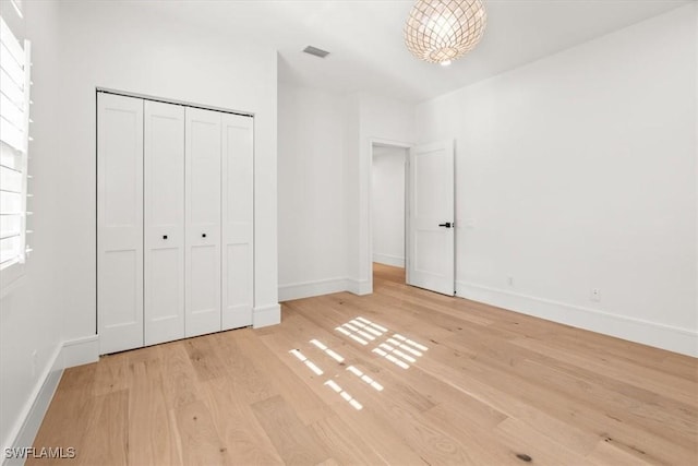 unfurnished bedroom with light wood-type flooring, baseboards, and a closet
