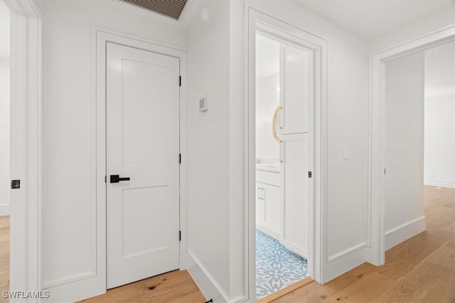 hallway with light wood-type flooring and baseboards