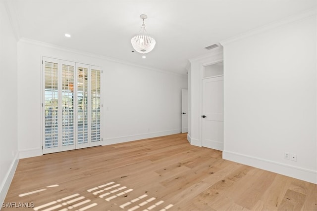 unfurnished room featuring a chandelier, light wood-type flooring, and crown molding