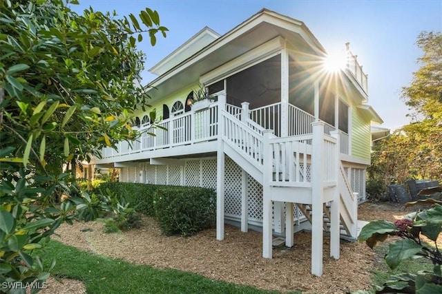 view of property exterior with stairway, a sunroom, and a chimney