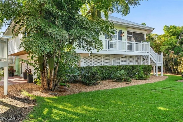 rear view of property featuring a sunroom, a yard, and stairs