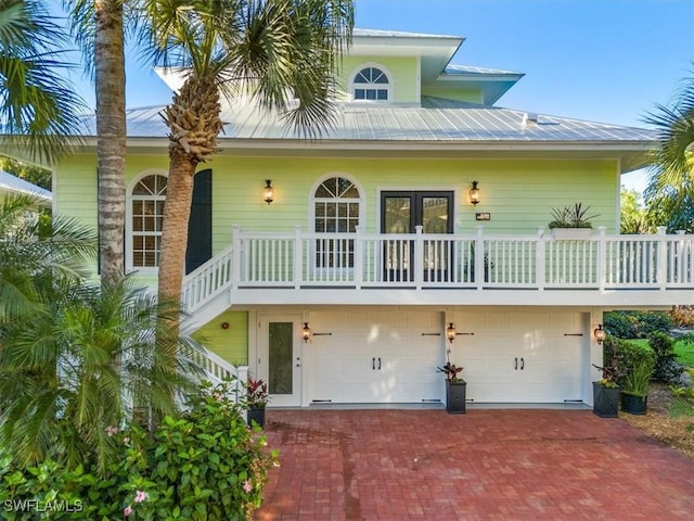 back of house with an attached garage, metal roof, and decorative driveway