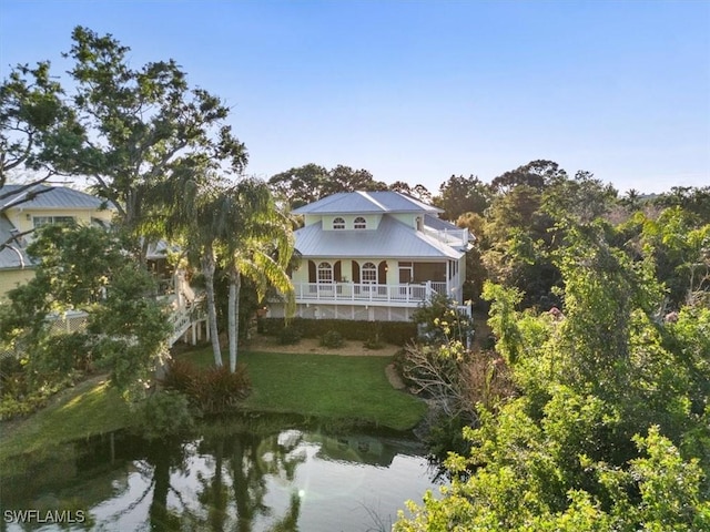 rear view of property featuring a yard, covered porch, a water view, and metal roof