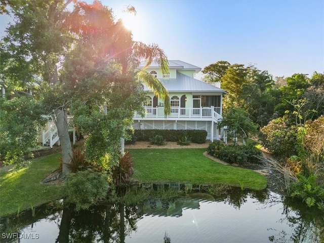 back of house with a water view and a yard