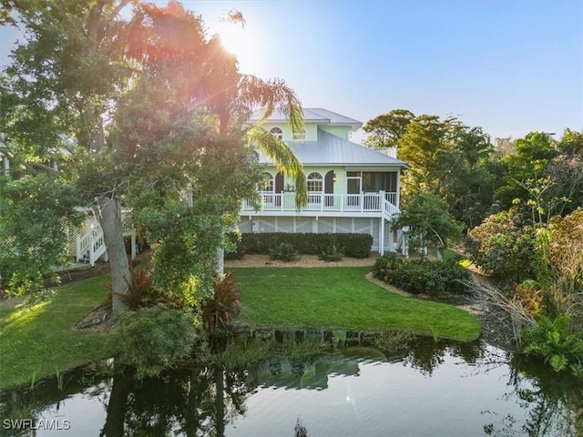 back of house with a lawn, a water view, and a sunroom