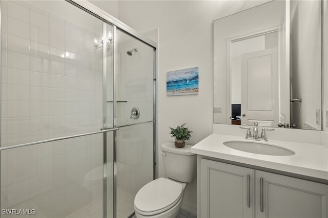 bathroom featuring vanity, toilet, and a shower with shower door