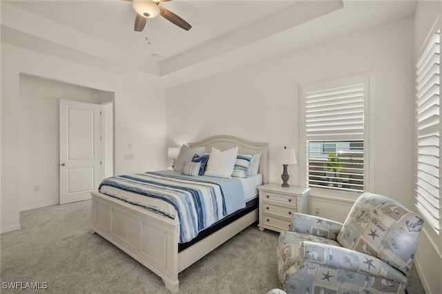 carpeted bedroom with a raised ceiling and ceiling fan