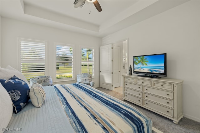 carpeted bedroom with a raised ceiling and ceiling fan