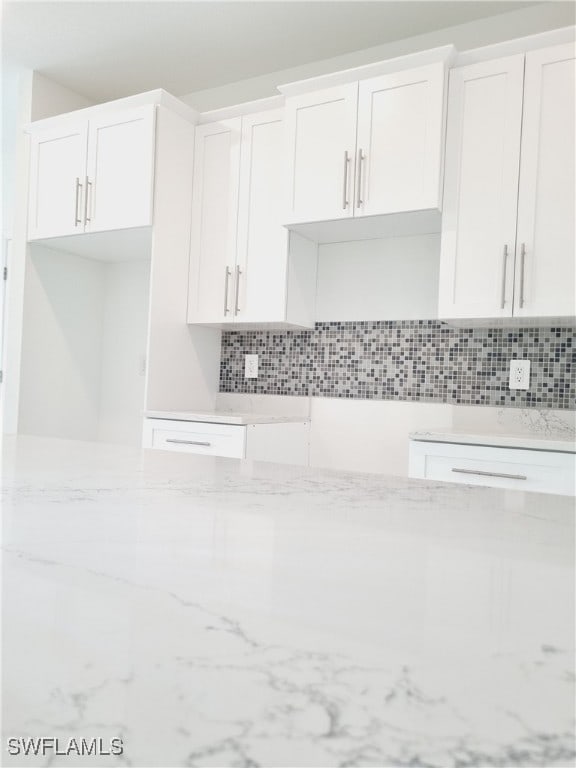 interior space with white cabinets, light stone counters, and tasteful backsplash