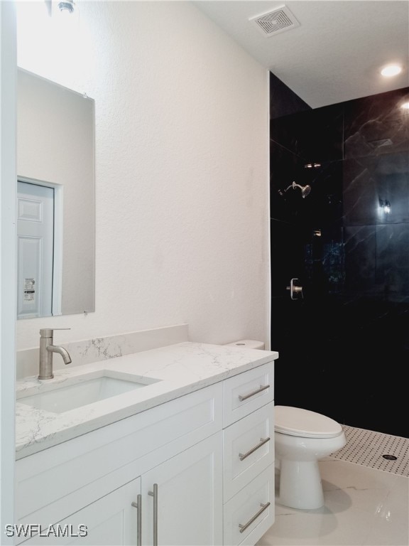 bathroom with tile patterned floors, vanity, toilet, and a tile shower