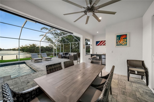 view of patio / terrace with an outdoor living space, ceiling fan, a water view, and glass enclosure