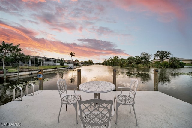 patio terrace at dusk featuring a water view