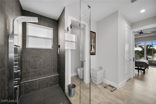 bathroom featuring tiled shower, toilet, and ceiling fan