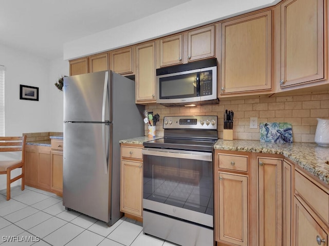 kitchen featuring appliances with stainless steel finishes, tasteful backsplash, light tile patterned floors, and light stone counters