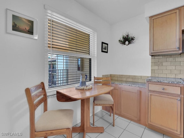 kitchen featuring decorative backsplash, light stone counters, and light tile patterned floors