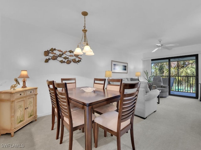 carpeted dining area with ceiling fan with notable chandelier