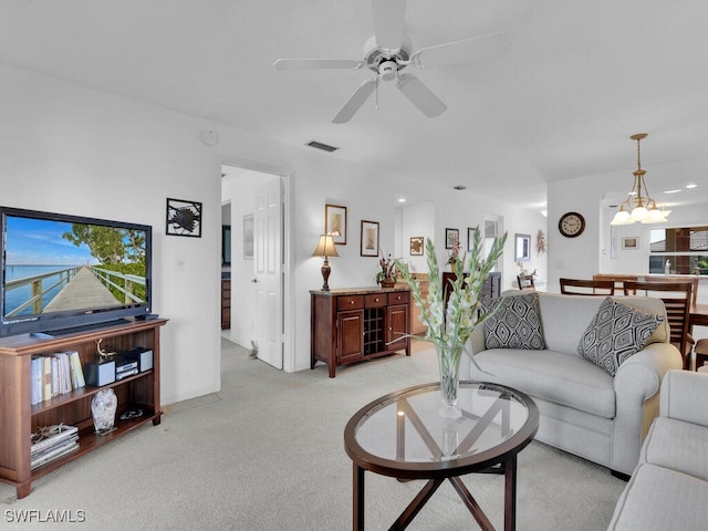 carpeted living room featuring ceiling fan with notable chandelier