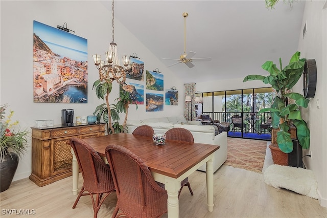 dining space featuring ceiling fan with notable chandelier, light wood-type flooring, and vaulted ceiling