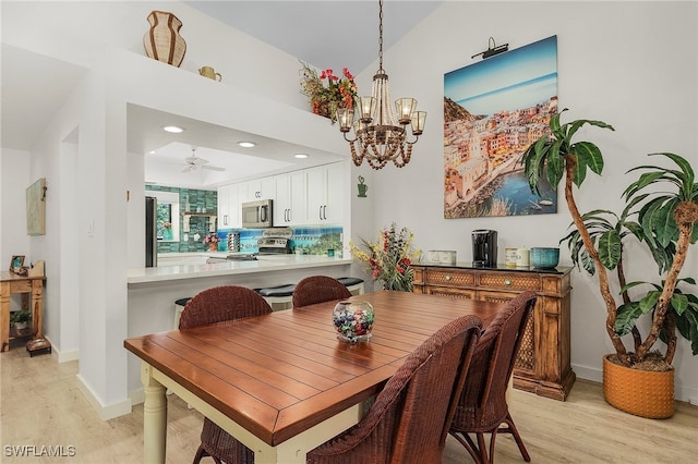 dining area with light wood-type flooring and ceiling fan with notable chandelier