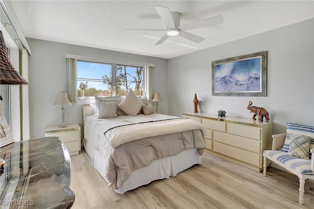 bedroom featuring ceiling fan, light hardwood / wood-style floors, and a textured ceiling