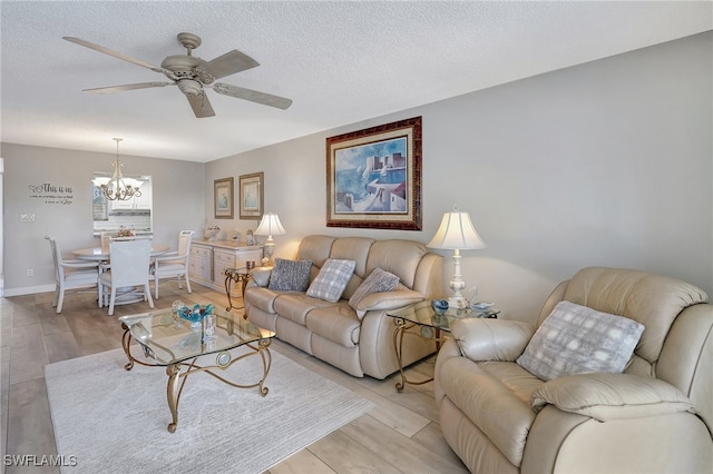 living room featuring a textured ceiling, ceiling fan with notable chandelier, and light wood-type flooring