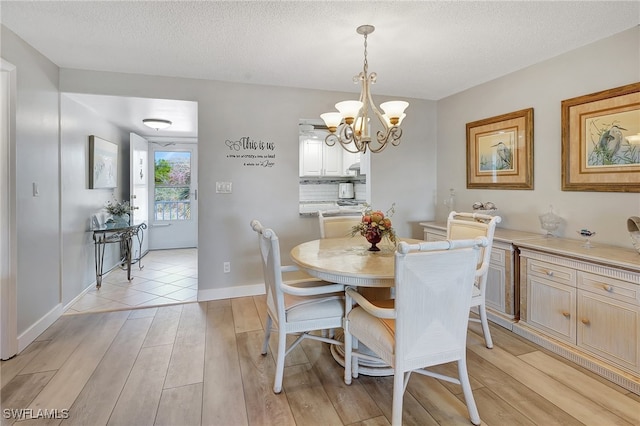 dining space featuring a chandelier, a textured ceiling, and light wood-type flooring