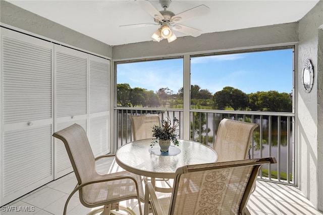 sunroom / solarium featuring a water view and ceiling fan