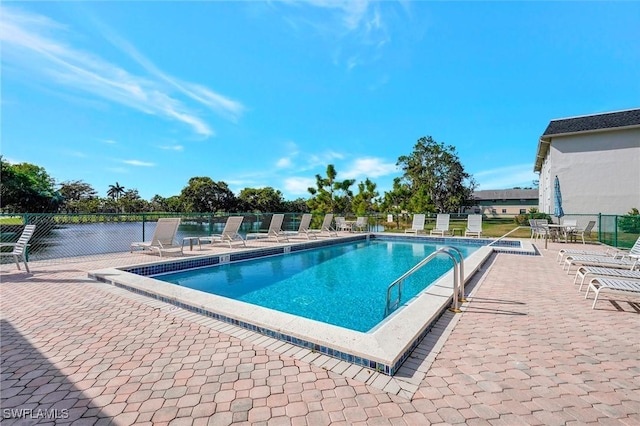 view of swimming pool featuring a water view and a patio area